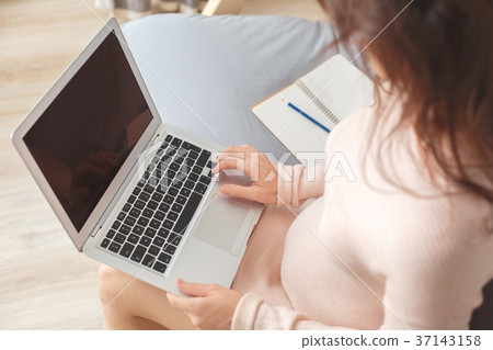 Young pregnant woman on the sofa at home in winter Young pregnant woman on the sofa at home in winter 37143158
