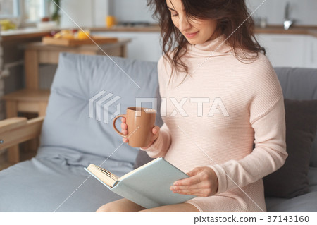 Young pregnant woman on the sofa at home in winter Young pregnant woman on the sofa at home in winter 37143160