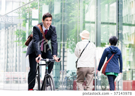 Cheerful young employee riding an utility bicycle Cheerful young employee riding an utility bicycle 37143978