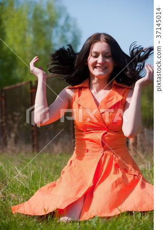 Pretty girl in orange dress on grass 37145014