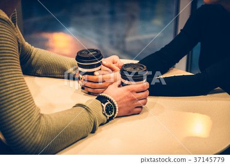 Couple holding hands and drinking coffee 37145779