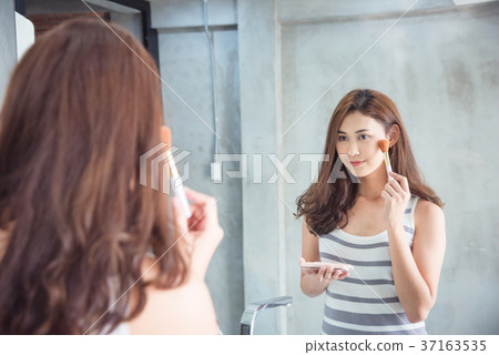 Woman making up her face in bathroom Woman making up her face in bathroom 37163535