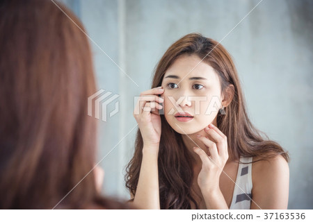 woman unhappy while watching her face in mirror woman unhappy while watching her face in mirror 37163536