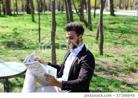 Successful businessman reading newspaper at lunch. 37166648