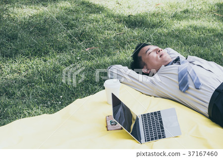 Asian businessman is sleeping on a lawn Asian businessman is sleeping on a lawn 37167460