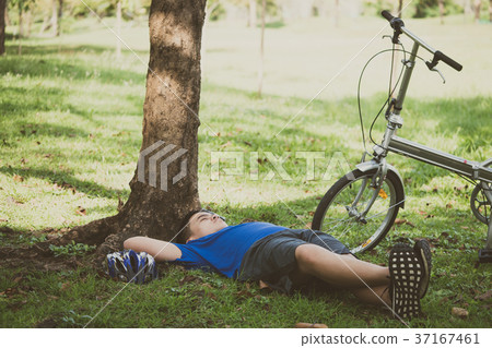 A young man is relaxing after cycling in a park. A young man is relaxing after cycling in a park. 37167461