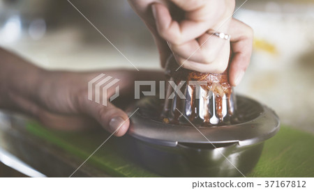 A hand squeezing juice from an orange on a manual A hand squeezing juice from an orange on a manual 37167812