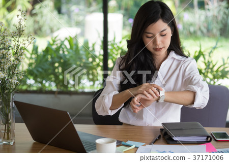 businesswoman look at her watch at workplace. startup woman check time on wristwatch at office. young female entrepreneur with paperwork on table. businesswoman look at her watch at workplace. startup woman check time on wristwatch at office. young female entrepreneur with paperwork on table. 37171006
