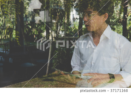 businessman using tablet computer at workplace. startup man working with touchpad at office. young male entrepreneur holding pad standing at window in cafe businessman using tablet computer at workplace. startup man working with touchpad at office. young male entrepreneur holding pad standing at window in cafe 37171168