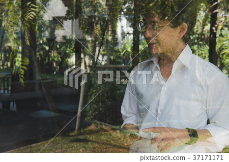 businessman using tablet computer at workplace. startup man working with touchpad at office. young male entrepreneur holding pad standing at window in cafe businessman using tablet computer at workplace. startup man working with touchpad at office. young male entrepreneur holding pad standing at window in cafe 37171171