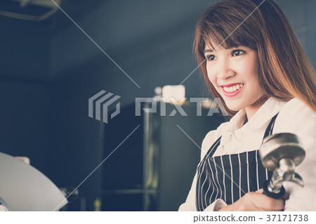 small business owner standing at counter in coffee shop. female barista wearing apron smiling at bar in cafe. food service, restaurant concept. small business owner standing at counter in coffee shop. female barista wearing apron smiling at bar in cafe. food service, restaurant concept. 37171738