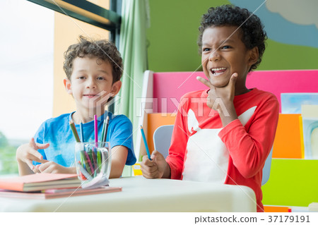 kid sit on table and coloring in book 37179191