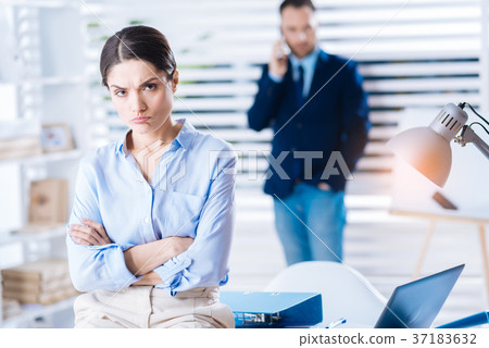 Upset woman pouting her lips while sitting with 37183632