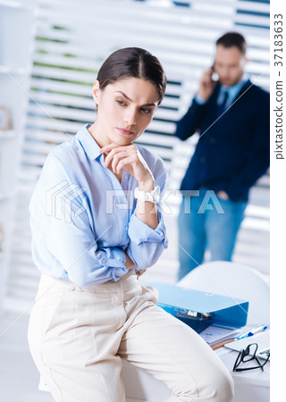 Upset woman sitting on the table in her office and 37183633
