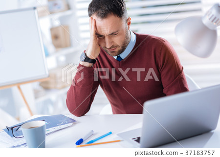 Young tired man feeling unwell while being at his 37183757