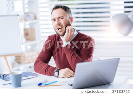 Unhappy man feeling terrible toothache while 37183765