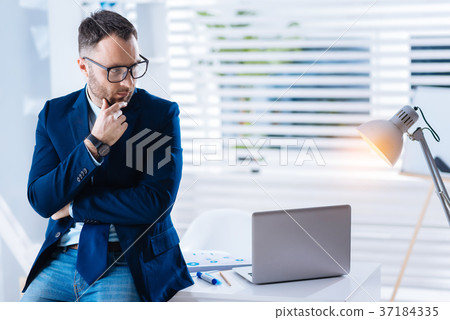 Calm smart man in glasses looking at the lamp 37184335
