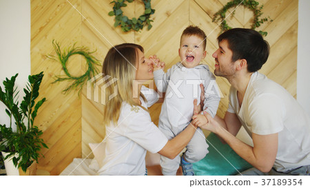 A young family with little son play on bed in the 37189354