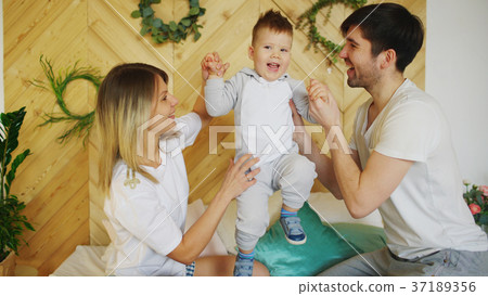 A young family with little son play on bed in the A young family with little son play on bed in the 37189356