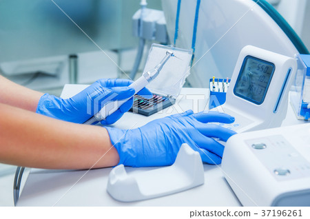 Assistant's hands configures dental equipment Assistant's hands configures dental equipment 37196261