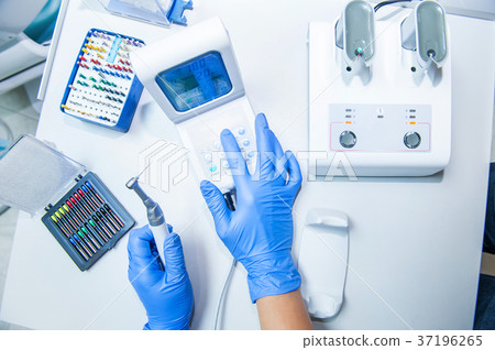 Assistant's hands configures dental equipment  37196265