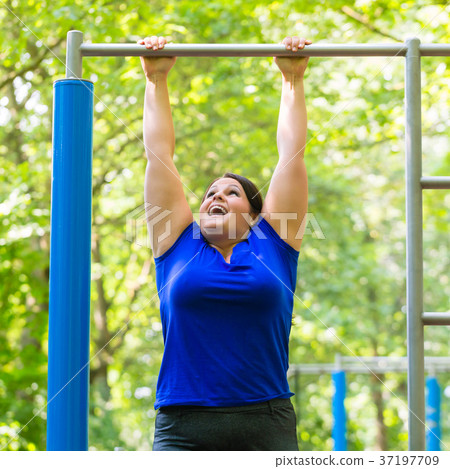 plump woman making sport exercises at high bar plump woman making sport exercises at high bar 37197709