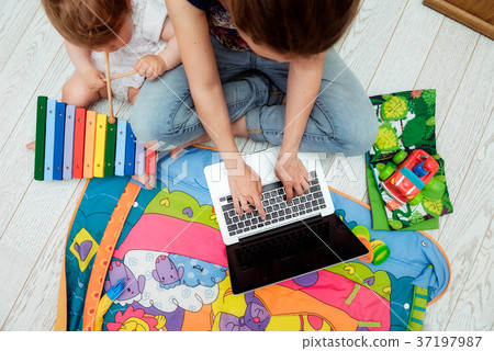 young mother working on laptop with toddler child young mother working on laptop with toddler child 37197987