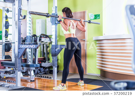 Fit woman doing squat with barbell in the gym. Fit woman doing squat with barbell in the gym. 37200219
