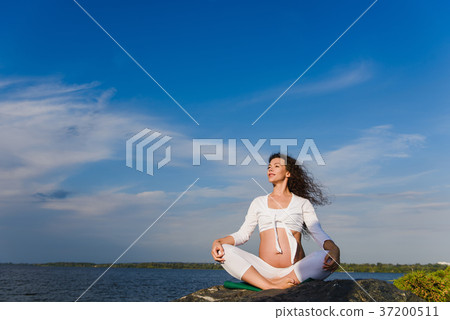 Meditating pregnant woman outdoors. Meditating pregnant woman outdoors. 37200511