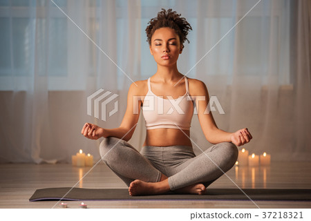 Peaceful african girl meditating in cozy room near Peaceful african girl meditating in cozy room near 37218321
