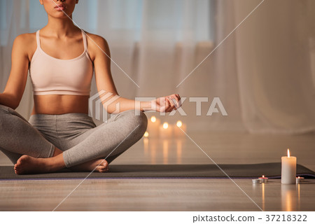 Serene young woman meditating on carpet in cozy Serene young woman meditating on carpet in cozy 37218322