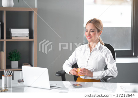 Cheerful businesswoman drinking cup of beverage Cheerful businesswoman drinking cup of beverage 37218644