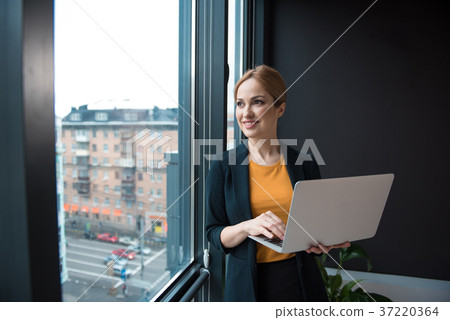 Happy businesswoman noting in laptop Happy businesswoman noting in laptop 37220364