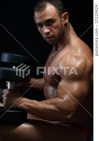 Muscular bodybuilder posing with weights Muscular bodybuilder posing with weights 37220424