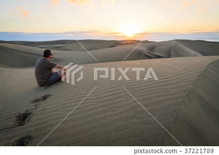Man sitting and relaxing on sand dunes. 37221789
