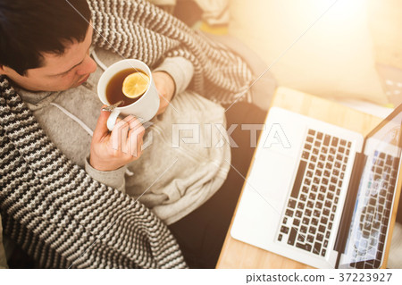 Young man laying in bad with laptop and cup of tea Young man laying in bad with laptop and cup of tea 37223927