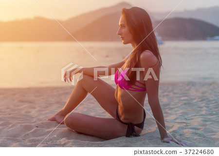Slim tanned model in bikini posing on beach Slim tanned model in bikini posing on beach 37224680