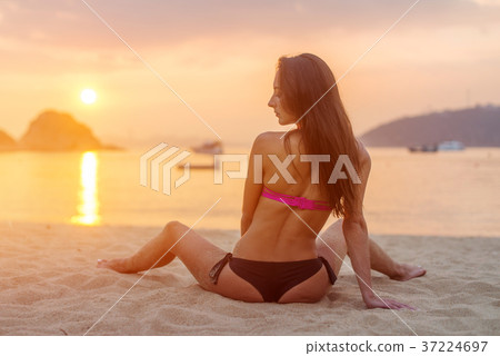 Rear view of slim female model sitting on seashore Rear view of slim female model sitting on seashore 37224697