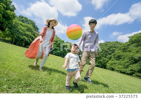 Three-person family playing in a fresh green park 37225573