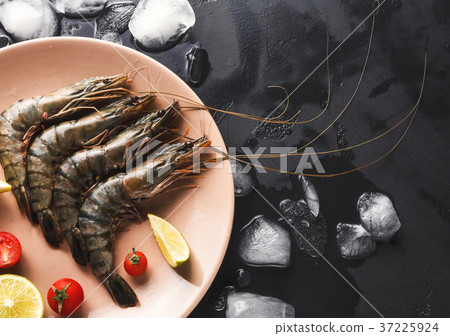 Raw shrimps with lemon on black background Raw shrimps with lemon on black background 37225924