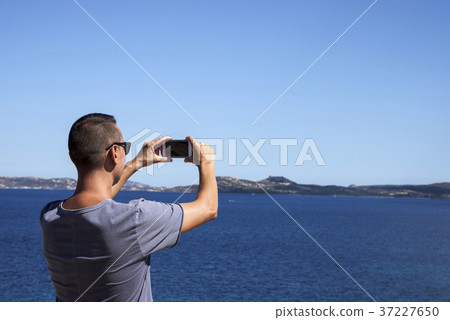 man taking a photo of the sea in Sardinia, Italy 37227650