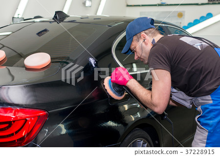 A man polishes a black car 37228915