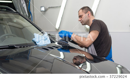 A man polishes a black car A man polishes a black car 37229024