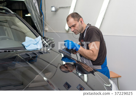 A man polishes a black car A man polishes a black car 37229025