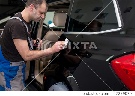 A man polishes a black car 37229070