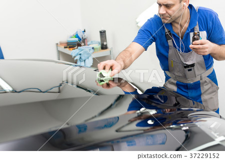 Man on a car wash polishing car with a polish machine Man on a car wash polishing car with a polish machine 37229152