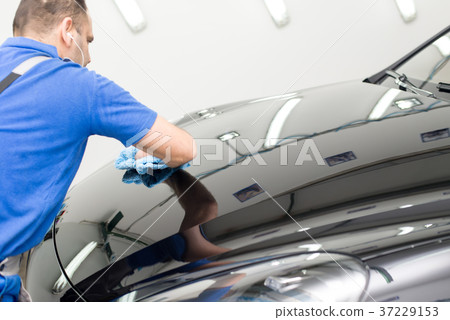 Man on a car wash polishing car with a polish machine Man on a car wash polishing car with a polish machine 37229153