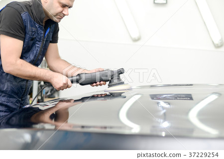 Man on a car wash polishing car with a polish machine Man on a car wash polishing car with a polish machine 37229254