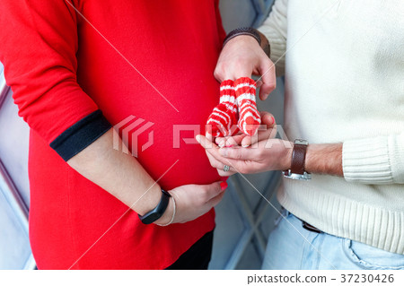 Pregnant couple holding shoes in hands Pregnant couple holding shoes in hands 37230426