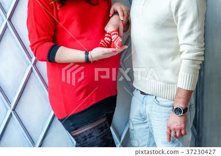 Pregnant couple holding shoes in hands Pregnant couple holding shoes in hands 37230427
